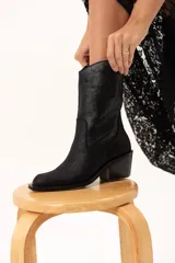 Bota de caña media con diseño estilo western, confeccionada en cuero con acabado texturado tipo craquelado. Cuenta con taco medio y tiradores laterales para facilitar el calce.