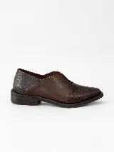 Mocasines de charol color bordó, de diseño vanguardista con corte asimétrico en el empeine, abertura en V, punta fina y suela plana con pequeño tacón.