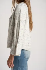 Sweater de punto con textura de ochos, color gris melange con motas oscuras, cuello redondo y mangas largas con terminación acampanada.