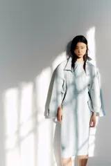 Vestido midi celeste de punto suave, sin mangas y con escote halter con detalle de nudo y fruncidos al frente. Cuenta con costuras laterales fruncidas que generan un efecto drapeado.
