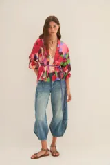 Kimono de corte holgado con estampado floral abstracto en tonos fucsia, rosa, verde y azul. Presenta mangas tres cuartos y diseño abierto frontal.