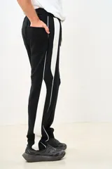 Pantalón de jogging negro con franjas blancas laterales y cordón ajustable en la cintura.