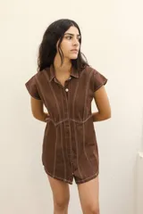Vestido corto camisero de jean azul oscuro con cuello clásico, cierre frontal con botones y mangas cortas. Presenta costuras decorativas en color blanco.