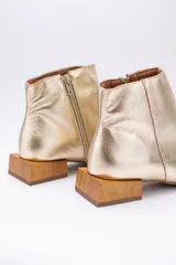 Botín de cuero dorado con punta fina y taco bajo cuadrado de madera.