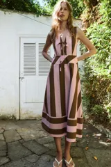 Vestido midi sin mangas, con escote en V y detalle de lazada frontal. Presenta un diseño de rayas verticales en tonos rosado y marrón, con un panel inferior de rayas horizontales.
