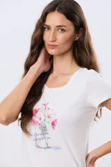 Remera blanca de manga corta y cuello redondo, con estampa frontal de flores en tonos rosados dentro de un frasco de vidrio y detalles de letras bordadas.