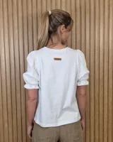 Remera blanca con cuerpo de algodón y mangas cortas abullonadas de broderie, con cuello redondo.