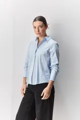 Camisa de algodón blanca, de calce relajado, con cuello clásico, mangas largas y cierre frontal con botones.
