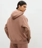 Buzo deportivo oversized con capucha, confeccionado en mezcla de algodón y poliéster. Presenta bolsillo frontal tipo canguro, mangas con recortes en los hombros y puños y ruedo con terminación en rib.