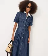 Vestido midi de jean azul, de manga corta, con bolsillos frontales con solapa, cierre frontal de botones y cinturón ajustable para anudar en la cintura.