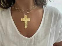 Collar plateado con eslabones ovalados y dije de cruz dorada con textura martillada.