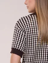Cardigan de punto con patrón geométrico bicolor en gris y blanco, de manga corta, cuello polo y cierre frontal con botones nacarados.