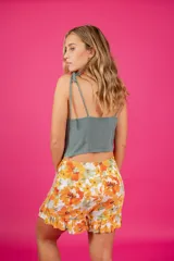 Short con diseño de pollera, tiro medio, estampado floral en tonos violeta, azul y rosado. Presenta detalle de aro de madera en la cintura, cierre lateral oculto y volados en la parte inferior.