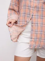 Camisa oversize de manga larga con estampado a cuadros en tonos rosado, amarillo y blanco, cuello camisero y cierre frontal con botones.