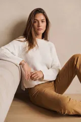Sweater de punto en color blanco, de corte oversize y diseño de manga larga con cuello redondo. Presenta un detalle de costura lateral en contraste.