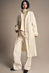 Gabardina oversize color blanco roto, con cuello solapa, manga larga y bolsillos laterales ocultos. Presenta cintura ajustable con cordones a tono y forro interior.