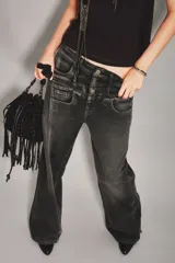 Jean de corte tomboy en color negro con efecto lavado, diseño de tiro alto con doble botón frontal y costuras verticales decorativas en los laterales.