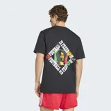 Remera negra de algodón con cuello redondo y mangas cortas. Presenta el logo del Trifolio de Adidas en blanco en el pecho derecho y un parche circular con manos entrelazadas en colores rasta en el pecho izquierdo. Incluye un pequeño parche rectangular en la parte inferior derecha.
