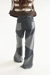 Jean de tiro medio con diseño de recortes en bloques de denim en tonos gris y negro, de corte recto.