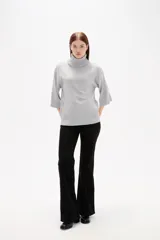 Polera de tejido de punto color gris, con cuello alto, mangas 3/4 y diseño holgado.