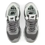 Championes urbanos New Balance modelo 574, color gris plateado con detalles en blanco, confeccionados con paneles de malla y cuero sintético metalizado. Cuentan con el característico logo "N" en el lateral y entresuela ENCAP.