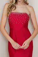 Vestido largo de fiesta color rojo, corte sirena, con escote strapless y detalle de pedrería brillante en el busto.