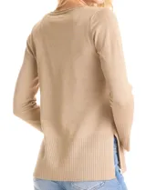 Buzo de tejido fino con acabado brillante de lurex, color beige, con escote en V, mangas largas con puños acanalados y ruedo con detalle de tejido acanalado más ancho.