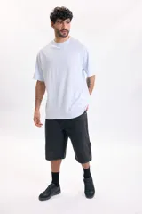 Remera celeste de manga corta y corte oversize, con estampa grande en la espalda que incluye un diseño abstracto de sol amarillo y textos negros.