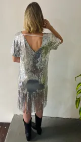 Vestido corto plateado de lentejuelas con escote en V, mangas cortas y flecos en el ruedo. Incluye choker y chaleco de red plateada.