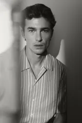 Camisa de manga corta con cuello abierto (cubano) y tapeta lisa, confeccionada en tejido suave de mezcla de lyocell. Presenta un patrón de rayas verticales blancas sobre un fondo verde menta o celeste pálido.