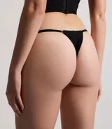 Bombacha colaless de encaje negro con diseño de hilo doble en la parte trasera y laterales finos ajustables. Presenta detalles de transparencia en el frente.