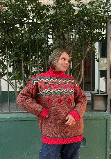 Buzo de cuello alto tejido en jacquard con diseño de personajes y motivos geométricos. Presenta una combinación de colores marrón, fucsia, verde y blanco, con puños y ruedo acanalados en color fucsia.