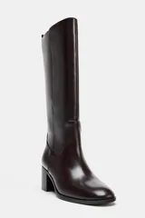 Bota alta de caña media en color marrón oscuro, con diseño minimalista, punta redonda y tacón bloque de madera. Cuenta con tirador trasero para facilitar el calce.