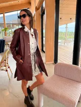 Campera tipo tapado de cuero ovino color bordó, con diseño holgado, cuello redondo y cierre frontal con botones a presión.