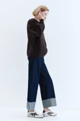 Buzo de tejido liso color marrón oscuro, con cuello redondo, hombros caídos y puños y bajo acanalados.