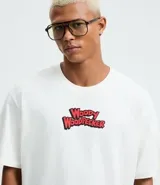 Remera boxy de algodón color blanco, con cuello redondo y mangas cortas. Presenta un estampado grande en la espalda del personaje El Pájaro Loco, con su nombre en rojo y un fondo azul y amarillo, y un globo de diálogo que dice "Guess Who?".