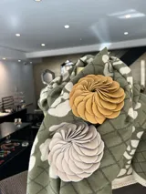 Broche con forma de flor color verde oliva, realizado artesanalmente en Italia con pétalos de cuero superpuestos. Se aplica con imán.