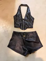 Mini short negro de cuero sintético con botón dorado.