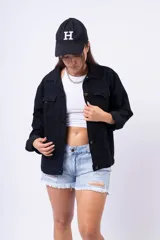 Campera de jean negra, de corte oversize, con cuello camisero, botones dorados y bolsillos frontales con solapa.