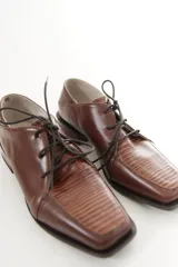 Zapato de charol negro de cuero vacuno con textura grabada tipo reptil, punta cuadrada y cordones al tono.