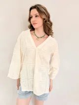 Blusa de broderie color blanco, con escote en V, mangas largas y diseño holgado.