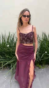 Pollera larga de gasa color bordó, con diseño de tiro alto, base fruncida y tajo lateral profundo decorado con volados verticales.