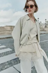 Chaqueta estilo bomber de cuero sintético en color beige, con cuello solapa, cierre frontal con cremallera, mangas largas y bajo elástico fruncido.