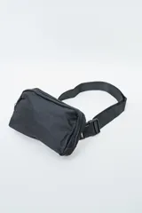 Bandolera negra de diseño rectangular, con cierre de cremallera y correa ajustable con hebilla plástica.