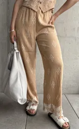Pantalón beige de corte recto con estampado de rombos blancos y cintura elastizada.