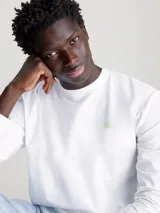 Remera de manga larga blanca con cuello redondo y un pequeño logo estampado en el pecho.