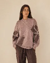 Buzo tejido de algodón y acrílico, color rosado con diseño floral en tonos marrones, de silueta amplia, cuello alto y terminaciones acanaladas.