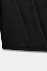 Top de escote asimétrico con detalle drapeado, confeccionado en tul negro. Presenta mangas largas acampanadas y estructura tipo corset en el torso con bajo redondeado.