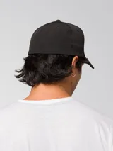 Gorro tipo gorra con visera curva de color negro, con el logo de CAT impreso en relieve en la parte delantera.