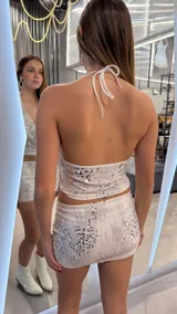 Top halter crop blanco con escote pronunciado y bordado de lentejuelas plateadas.